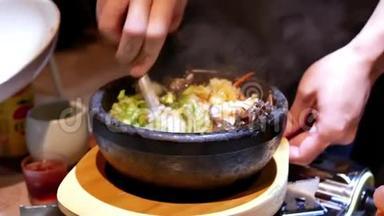 服务员在餐桌上为顾客搅拌韩国bibimbap的动作